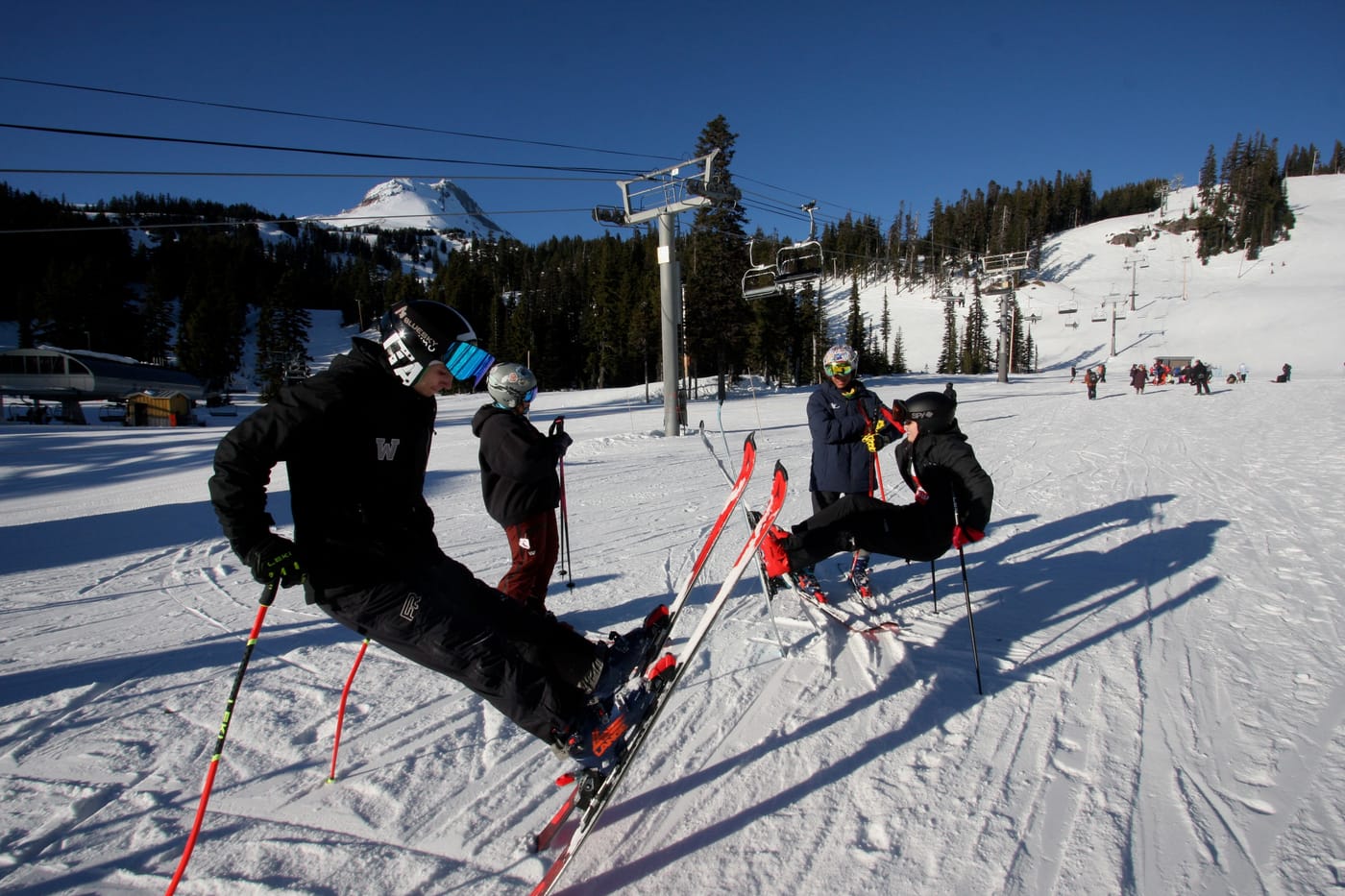 Racers clicking into skis below the chairlift with the summit of Mount Hood in the distance